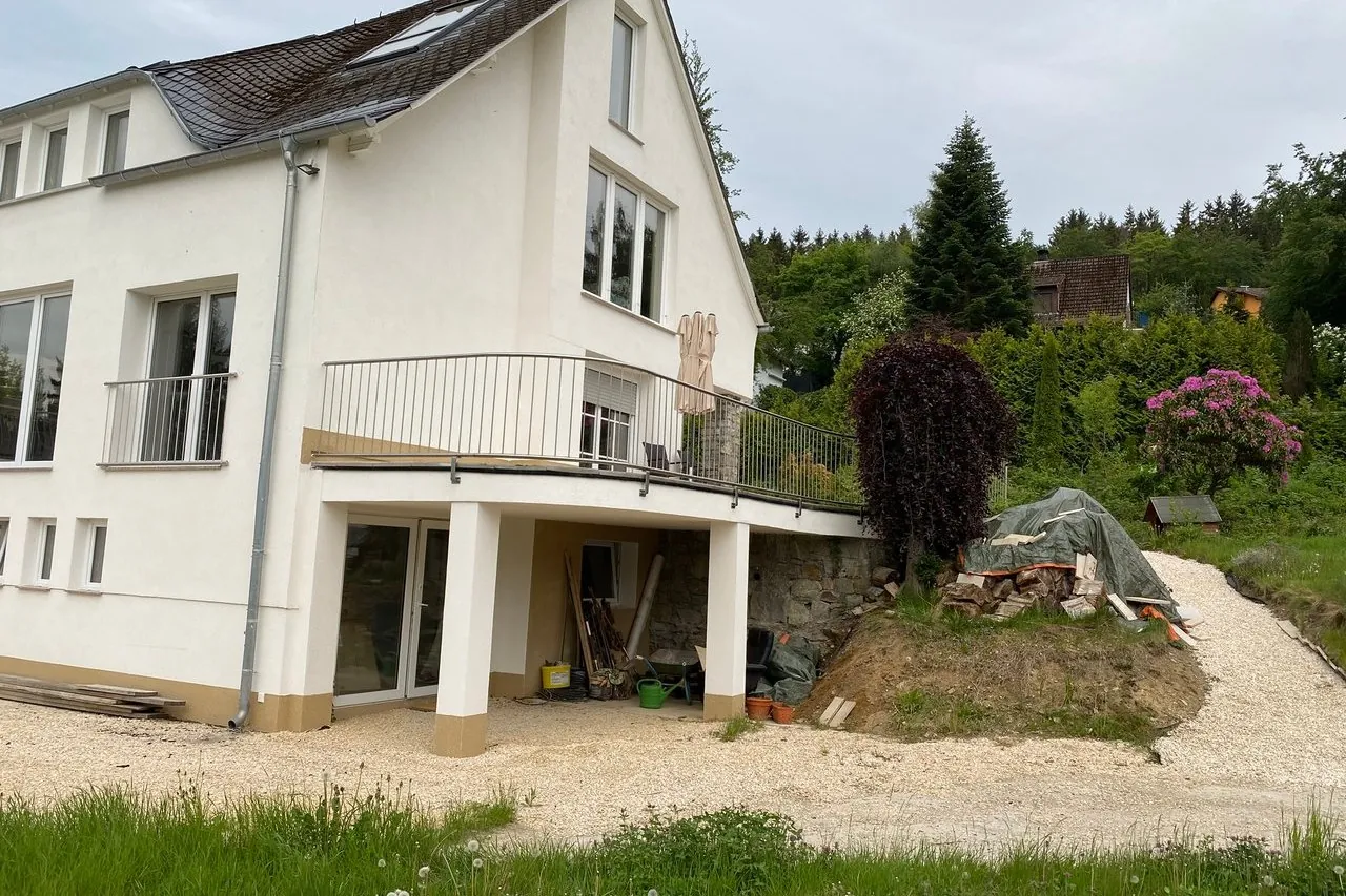 Angebauter Balkon mit Geländer an einem weißen Haus
