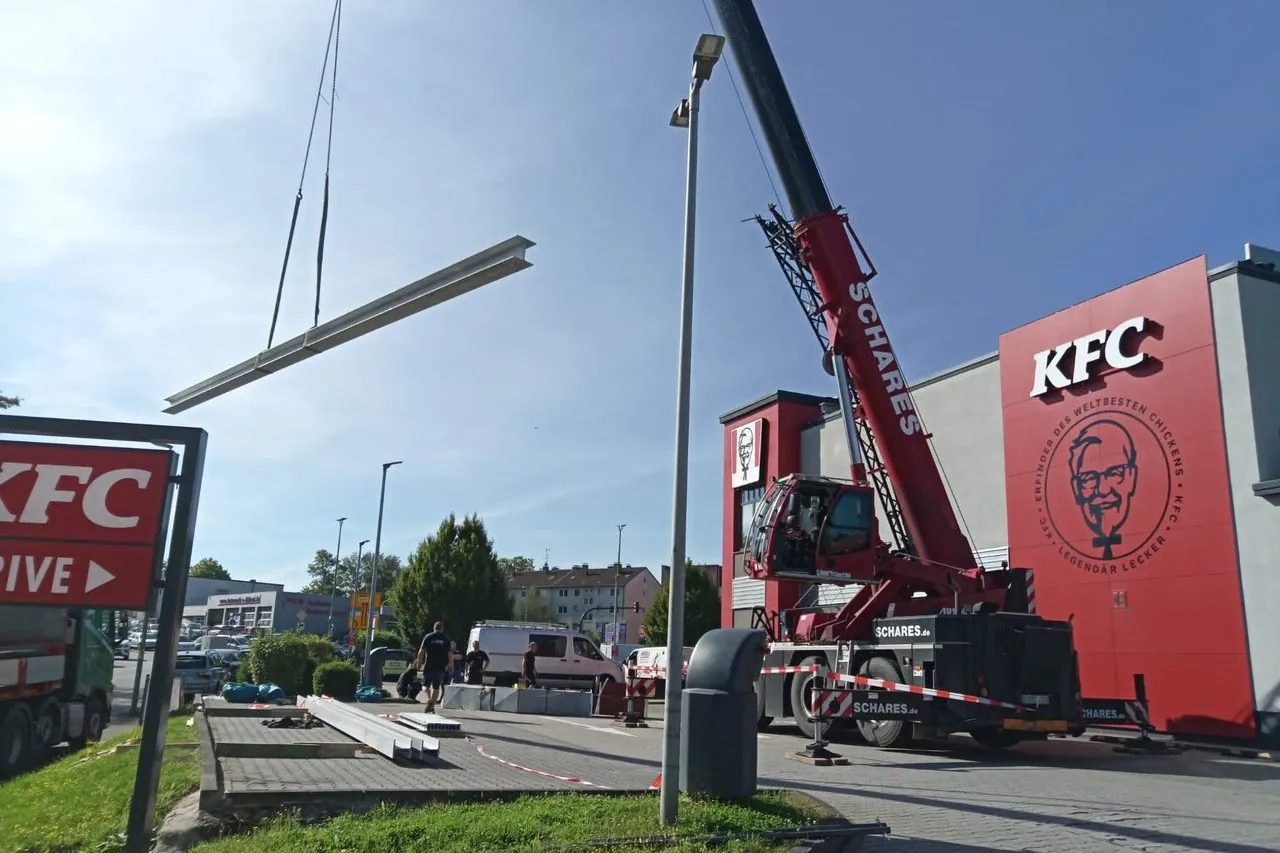 Autokran hebt einen Stahlträger bei der Montage einer Gewerbehalle